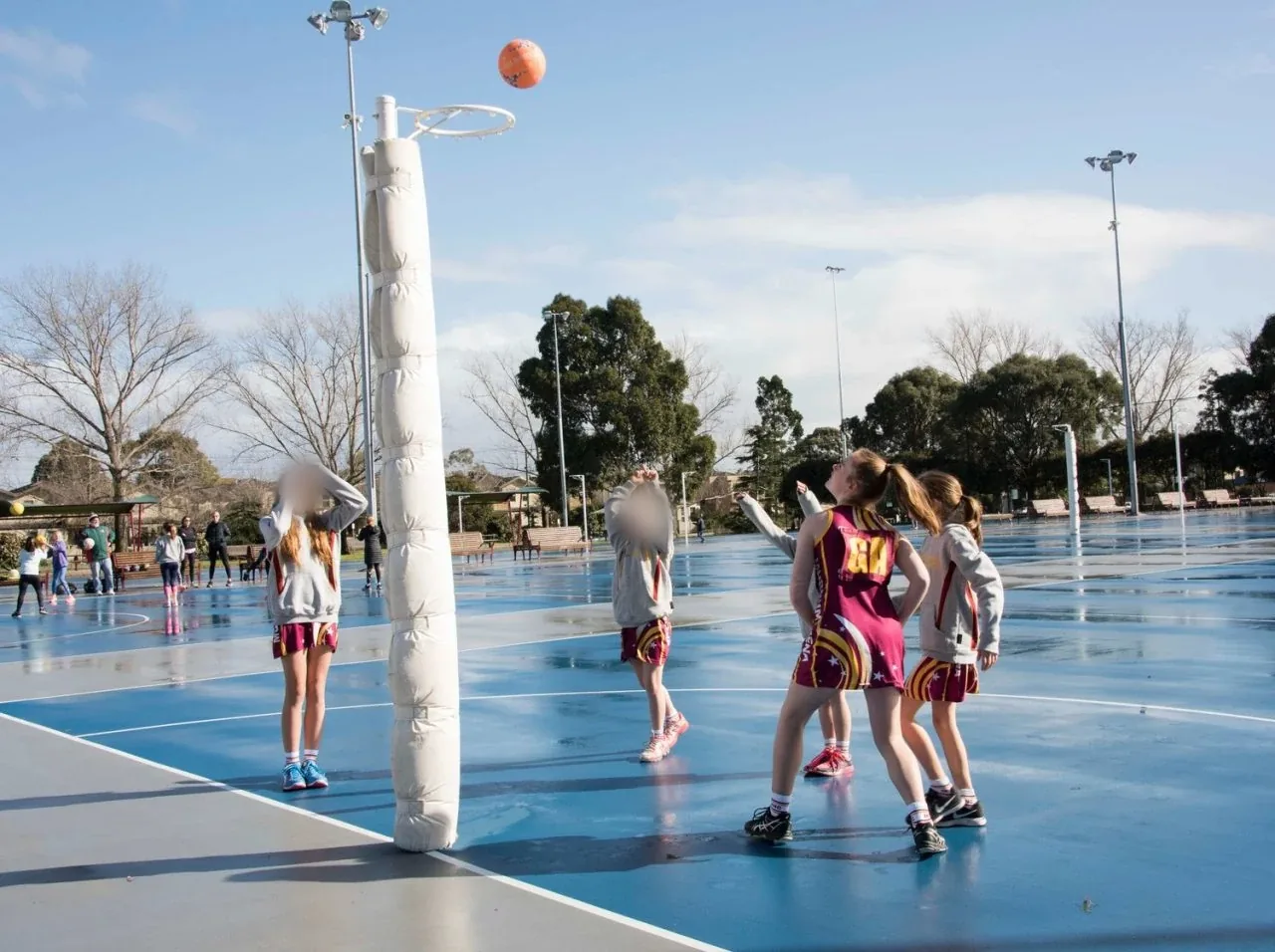Murrumbeena junior netballers training outdoors in the rain, on a court covered in water